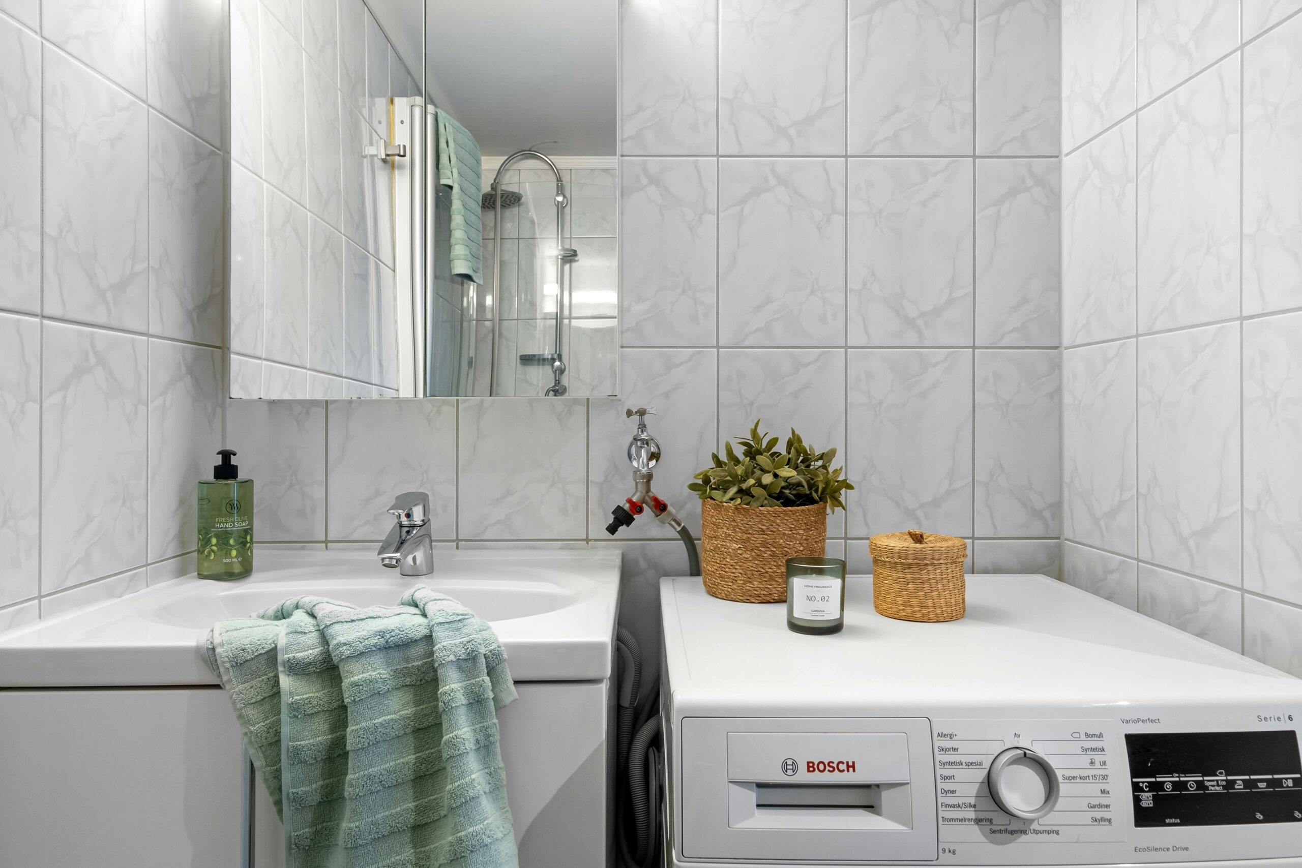 Pralka Bosch ustawiona obok umywalki w łazience